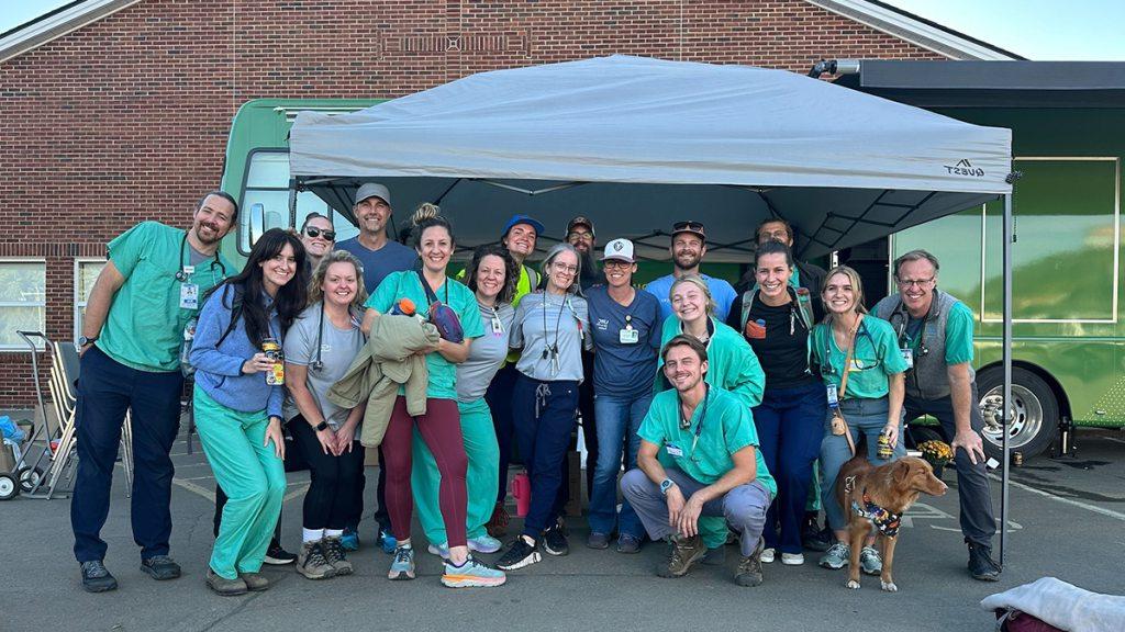 Individuals posing under tent set up for hurricane relief.